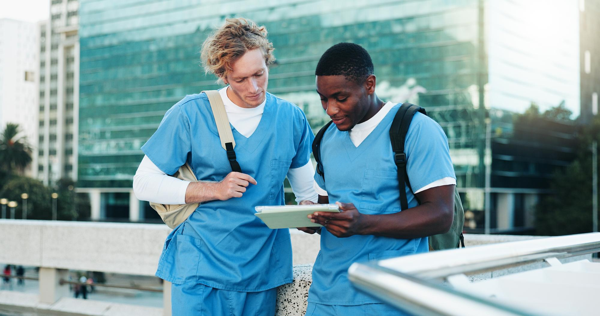 Two nurses reviewing information together outside a hospital